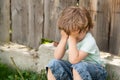 Sadness. Tears and crying. Children frustration. A sad boy is sitting in the garden. Loneliness.