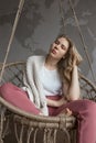 Sadness and thoughtfulness concept, beautiful young girl on the swing in cozy room, wearing plaid