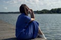 Sadness Woman Sitting by the River on pier. Empty place for text. Bad Day Concept Royalty Free Stock Photo