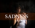 Sadness written on virtual screen. hand of young woman melancholy and sad at the window in the rain. Royalty Free Stock Photo