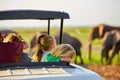 Safari holiday. Blond children watching african elephants from roof of a safari car.