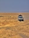 Safari jeep driving across parched Serengeti National Park, Tanzania Royalty Free Stock Photo