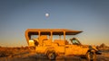 Safari vehicle at sunset with moon in the back, Onguma Game Reserve, Namibia. Royalty Free Stock Photo