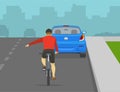 Safe bicycle riding. Back view of a cyclist showing turning gesture while cycling. Bicycle rider passing the parked car.