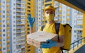 Safe food delivery. Courier in yellow uniform, protective mask and gloves delivers takeaway food