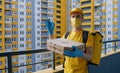 Safe food delivery. Courier in yellow uniform, protective mask and gloves delivers takeaway food