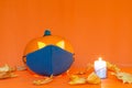 Safe Halloween 2020 during Covid-19 pandemc. Halloween carved luminous pumpkin,candle with face mask orange wall