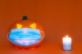 Safe Halloween 2020 during Covid-19 pandemc. Halloween carved luminous pumpkin,candle with face mask orange wall