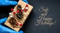 SAFE AND HAPPY HOLIDAYS text Holiday shopping. Festive gifts. Pandemic restriction. Winter shopping. Hand in protective gloves