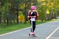 Safe riding a scooter with a helmet. The girl goes fast in the park