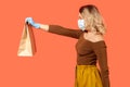 Safe shopping on quarantine. Side view woman in protective mask giving paper bag, food purchase Royalty Free Stock Photo