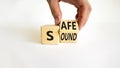 Safe and sound symbol. Businessman turns a wooden cube and changes the word `safe` to `sound` or vice versa. Beautiful white t