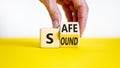 Safe and sound symbol. Businessman turns a wooden cube and changes the word `safe` to `sound` or vice versa. Beautiful yellow
