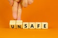 Safe or unsafe symbol. Concept word Safe Unsafe on wooden cubes. Businessman hand. Beautiful orange table orange background.