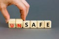 Safe or unsafe symbol. Concept word Safe Unsafe on wooden cubes. Businessman hand. grey table grey background. Business