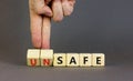 Safe or unsafe symbol. Concept word Safe Unsafe on wooden cubes. Businessman hand. Beautiful grey table grey background. Business