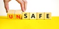 Safe or unsafe symbol. Concept word Safe Unsafe on wooden cubes. Businessman hand. Beautiful yellow table white background.