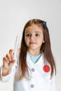 Portrait of cute beautiful girl, child in image of doctor wearing white lab coat with toy syringe isolated on white