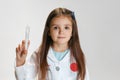 Portrait of cute beautiful girl, child in image of doctor wearing white lab coat with toy syringe isolated on white