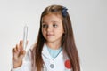 Portrait of cute beautiful girl, child in image of doctor wearing white lab coat with toy syringe isolated on white