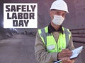 Safely Labor Day. Construction worker dressed in medical mask, uniform and white hardhat stands with clipboard at metro tunnel Royalty Free Stock Photo