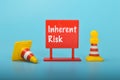 Safety cones and plastic board written with INHERENT RISK.Inherent risk refers to the risk that is inherent or inherent to a