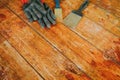 Safety gloves with paint brush and scrape tool placed on old wooden floor Royalty Free Stock Photo