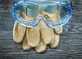 Safety gloves plastic goggles on wooden board