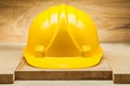 Safety headwear. yellow construction helmet on wood background