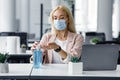 Safety and health protection at work in office. Millennial woman in protective mask with smart watch uses antiseptic at Royalty Free Stock Photo