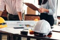 Safety helmets on the table at site construction. Architect, Engineer and businessman read planning background.