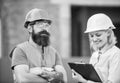 Safety inspector concept. Woman inspector and bearded brutal builder discuss construction progress. Construction project Royalty Free Stock Photo
