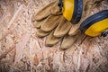 Safety leather gloves hard hat ear protectors on chipboard Royalty Free Stock Photo