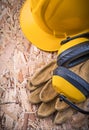 Safety leather gloves hard hat earmuffs on OSB Royalty Free Stock Photo