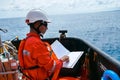 Safety officer, standing on an industrial ship, wearing overalls, a helmet, safety goggles and holding a clipboard with checklists Royalty Free Stock Photo