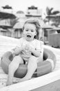 Safety, rescue and help concept. Happy child sit in ring buoy on sunny day. Little boy with lifebuoy on tropical beach Royalty Free Stock Photo