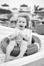 Safety, rescue and help concept. Happy child sit in ring buoy on sunny day. Little boy with lifebuoy on tropical beach Royalty Free Stock Photo