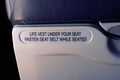 Safety sign on a commercial aircraft, indicating to fasten seat belt when seated. Royalty Free Stock Photo