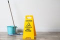 Safety sign with phrase Caution wet floor, mop and bucket indoors. Cleaning service Royalty Free Stock Photo