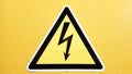 Safety sign yellow and black glued on a yellow wall. High voltage lightning in a triangle caution caution danger electricity death Royalty Free Stock Photo