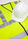 Safety vest and hard hat against white background