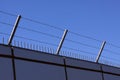 Safety wall with barbed wire and spikes on top of a fence provide security - blue sky background Royalty Free Stock Photo