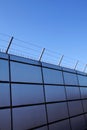 Safety wall with barbed wire and spikes on top of a fence provide security - blue sky background Royalty Free Stock Photo