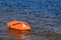 Safety on the water. A large orange buoy horizontally lies near the shore on the water of the Bay of the river