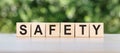 SAFETY word written on wooden blocks. The text is written in black letters and is reflected in the mirror surface of the table.