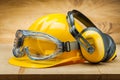 Safety of work. construction safety tools. yellow helmet blue goggles and earphones on wood background Royalty Free Stock Photo