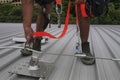 Trained worker clipping stainless industrial locking hook into fall arrest roof anchor point systems