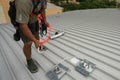 Trained worker clipping stainless industrial locking hook into fall arrest roof anchor point systems