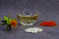 Safflower for cosmetics and spices to food. Saffron flowers and seeds in a pile on the table. Cosmetic vegetable oil in a glass