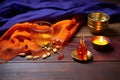 a saffron cloth, mala beads, and a brass diya oil lamp on a wooden board